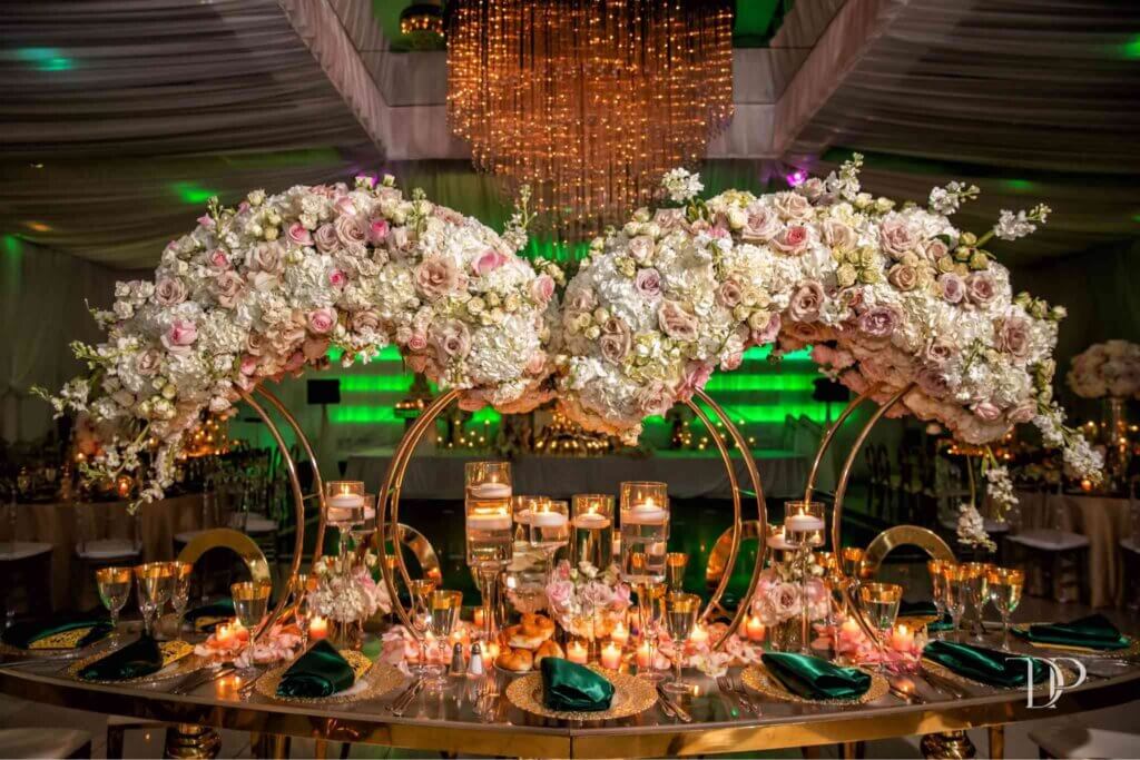 Luxurious wedding table with large cascading floral arrangements, gold accents, floating candles, and elegant place settings at Eden Regal Ballroom.