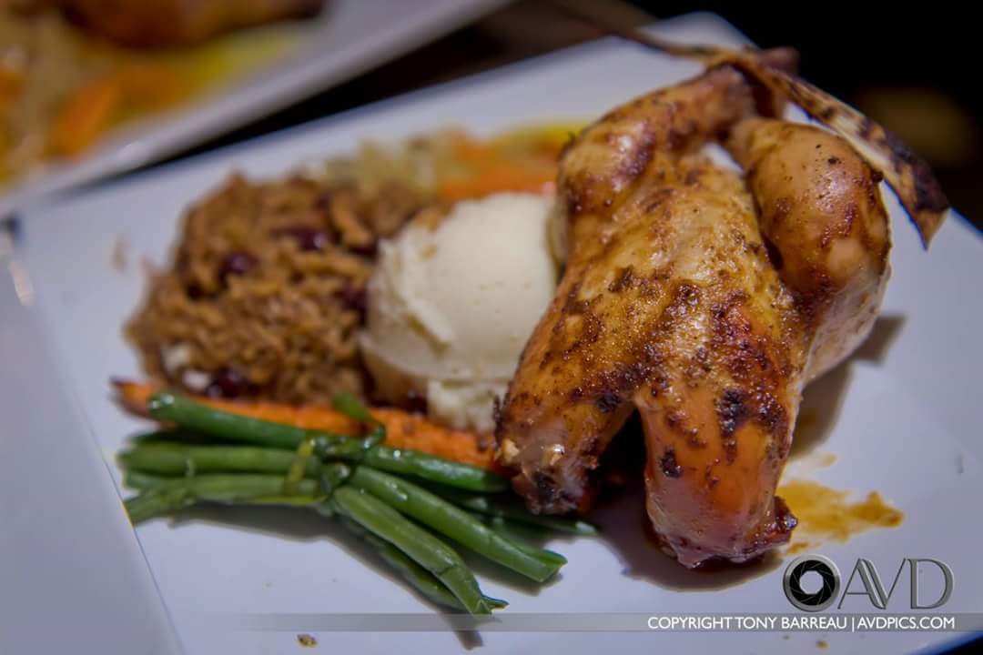 Roasted chicken served with mashed potatoes, rice and beans, green beans, and carrots on a white plate at a catered wedding
